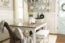a vintage farmhouse dining nook with open shelves, a wooden table, wooden and wicker chairs and a metal chandelier