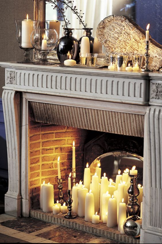 a vintage fireplace with pillar and tall and thin candles and with vintage candle holders in it
