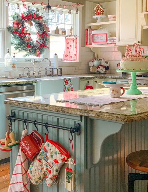 a vintage kitchen styled for Christmas, with neutral and blue cabinets, grey stone countertops, open shelves, a wreath and some other winter decor