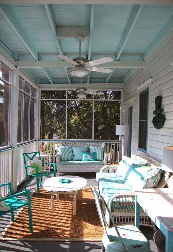 a vintage sunroom with white and turquoise furniture, potted textiles and a working nook with a desk