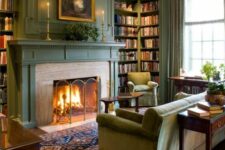 a welcoming vintage living room with green walls, a fireplace, built-in bookshelves, a green sofa and chairs, console tables