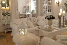 a white shabby chic living space with elegant mirrors and stylish furniture, candles, candle lanterns and white bloom