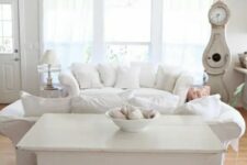 a white vintage living room with chic furniture, neutral textiles, a crystal chandelier and vintage accessories and decor