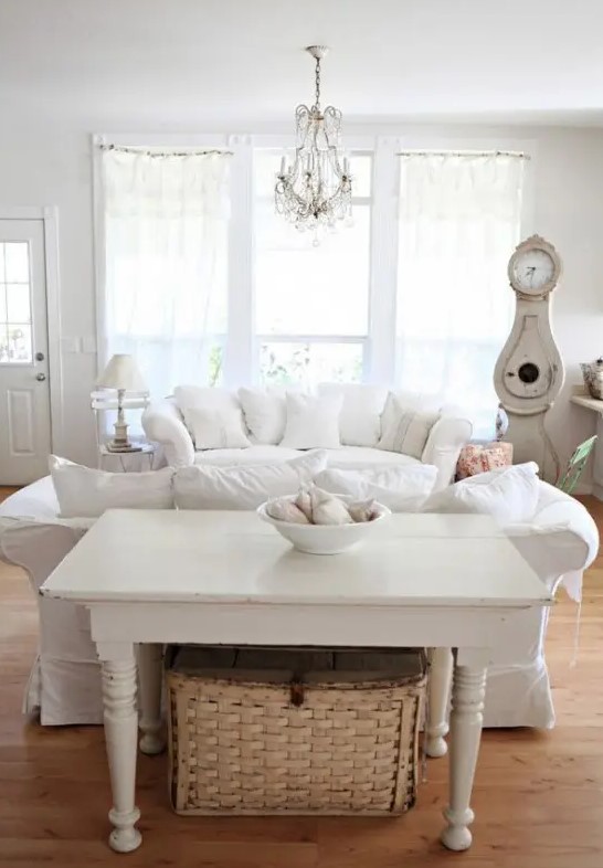 a white vintage living room with chic furniture, neutral textiles, a crystal chandelier and vintage accessories and decor
