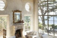 an airy and serene Provence living room with a fireplace, neutral furniture, wooden beams, bookshelves and a dining space