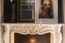 an ornate carved marble fireplace mantel filled with lit candles in front of a black backdrop that highlights them