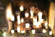 tree stumps with candles in glass candle holders and some greenery and pinecones around