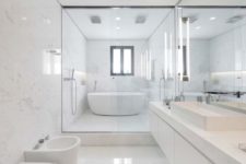 a chic minimalist bathroom clad with large scale white marble tiles, a floating marble vanity and white appliances