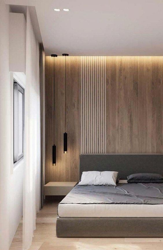 a chic minimalist bedroom with a light-stained accent wall, a grey bed, floating nightstands, black pendant lamps and built-in lights