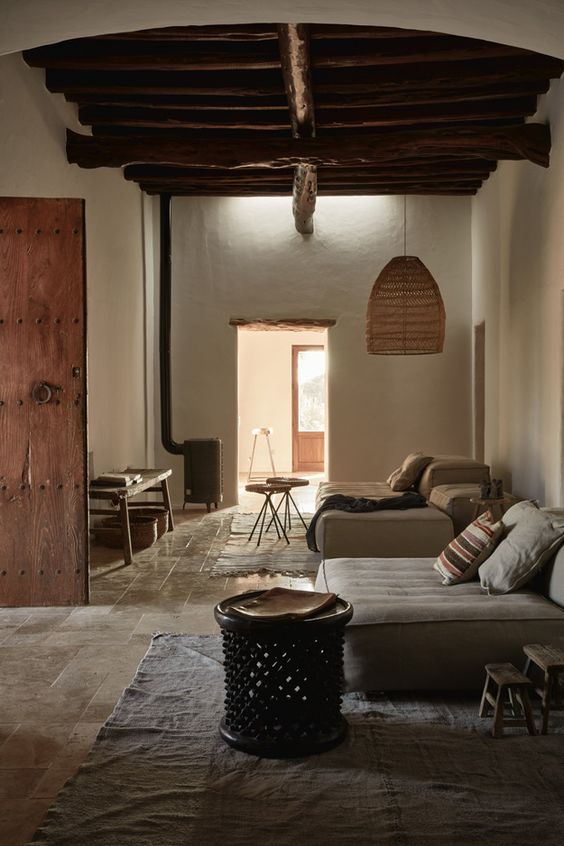 a chic wabi-sabi interior with white walls, a pendant lamp, a tile floor and a hearth