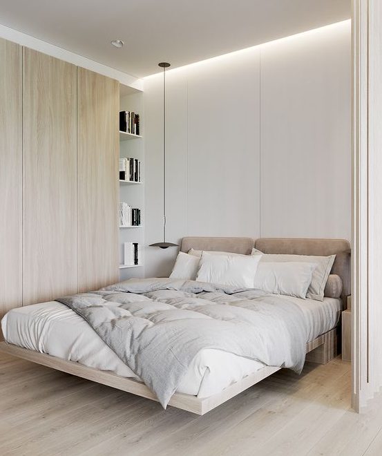 a cozy minimalist bedroom with a raised bed with an upholstered headboard, a sleek storage unit and pendant lamps