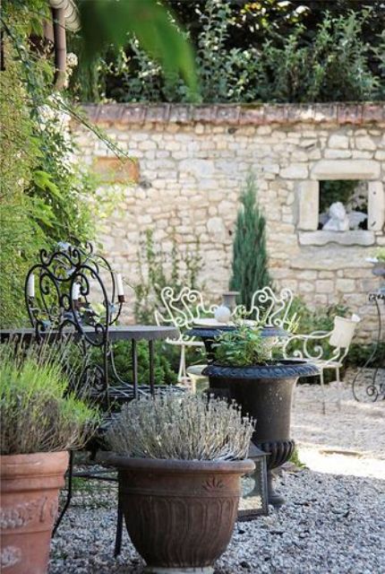 a delicate Provence terrace with black and white forged furniture, potted plants and blooms is a lovely space to spend time in