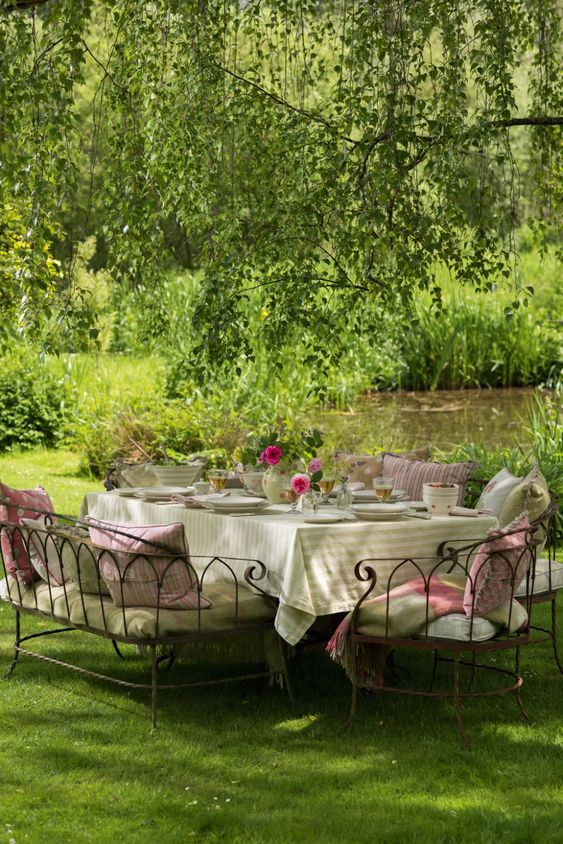 a delightful Provence outdoor space with a dining set of metal, with lots of cushions and pillows, bright blooms and greeneyr over it a delightful Provence outdoor space with a dining set of metal, with lots of cushions and pillows, bright blooms and greeneyr over it