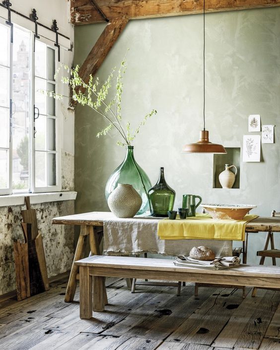 a dining space with wabi-sabi aesthetics, a wooden dining set, concrete wlals and a rough wooden floor plus vases