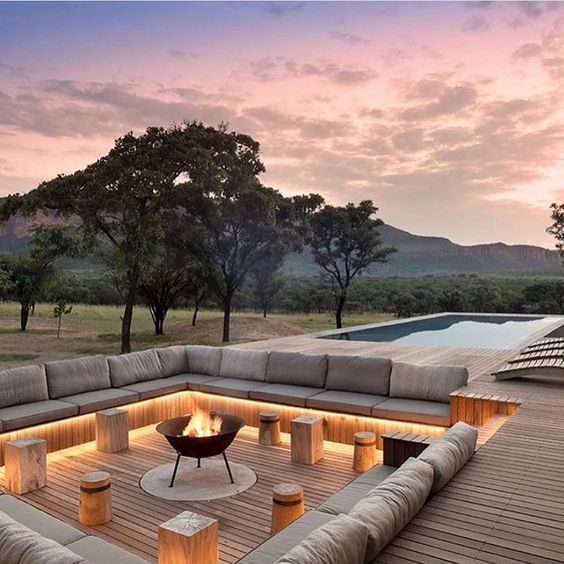 a gorgeous ultra-minimalist wooden deck clad with wood, with a built-in bench, built-in lights, a fire pit and small stools of wood