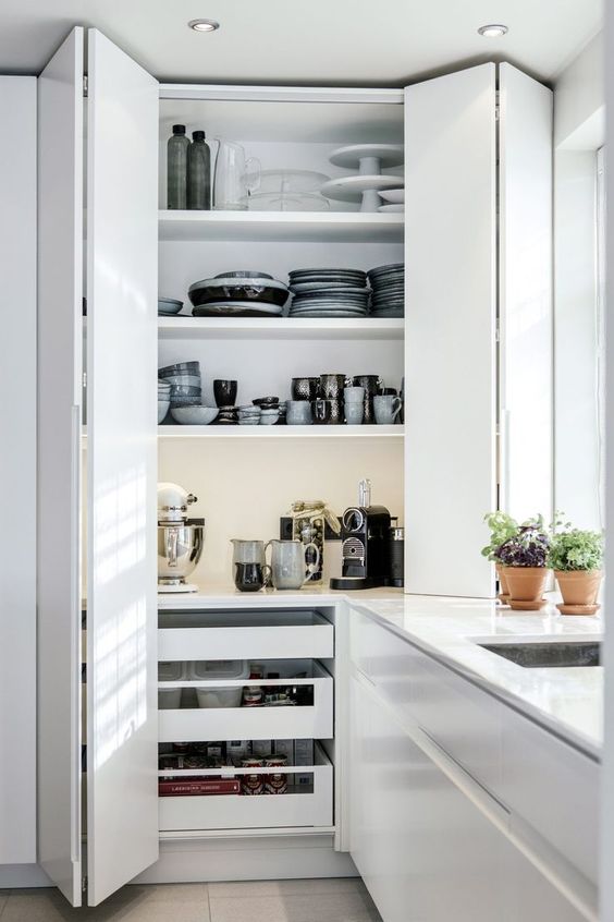 a large storage unit with folding doors, drawers and open shelves hides a lot of dishes, tableware and a coffee and tea station, additional lights make looking for the pieces easier
