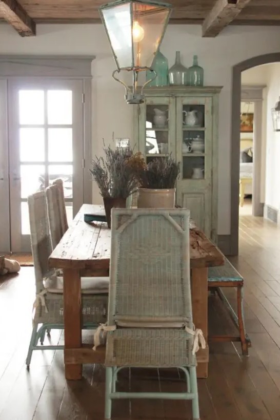 a lovely Provence dining room with a stained table and whitewashed woven chairs, a wooden bench, elegant pendant lanterns and a whitewashed buffet
