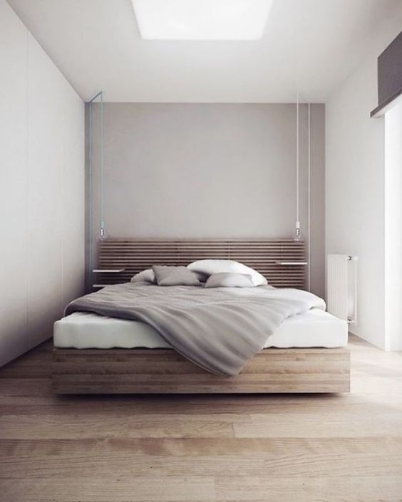 a minimalist bedroom with dove grey walls and a skylight, a stained bed with a slab headboard, neutral bedding and much light