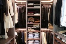a minimalist closet done in dark stained wood with much light, all the shelves are open and the drawers are glass ones