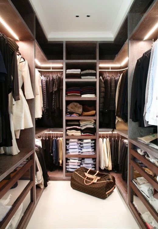 a minimalist closet done in dark stained wood with much light, all the shelves are open and the drawers are glass ones