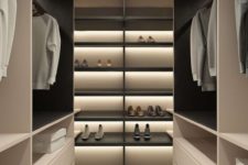 a minimalist closet done in light shades, with black shelves and much built-in light plus drawers