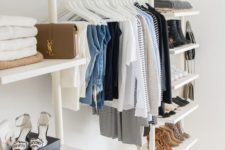 a minimalist closet with lots of open shelves, a dresser and lots of white clothes hangers plus boxes overhead