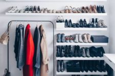 a minimalist closet with lots of open shelves for shoes, a dresser and a black holder for clothes hangers