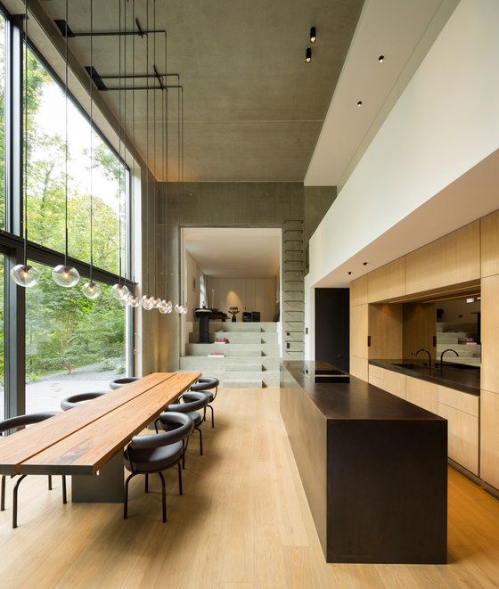 غرف طعام لعشاق الاناقة والبساطة A-minimalist-dining-room-with-a-glazed-wall-a-long-stained-table-graphite-grey-chairs-pendant-lamps-is-a-very-cool-and-lovely-space