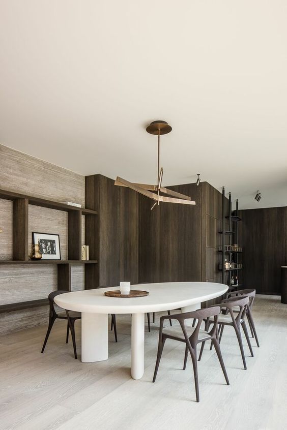 غرف طعام لعشاق الاناقة والبساطة A-minimalist-dining-room-with-a-grasscloth-wallpaper-wall-an-oval-table-and-dark-stained-chairs-a-catchy-brass-pendant-lamp