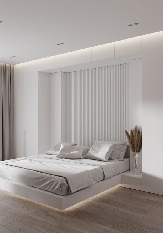 a minimalist neutral bedroom with a slab accent wall, a floating bed with lights, built-in nightstands and greige curtains