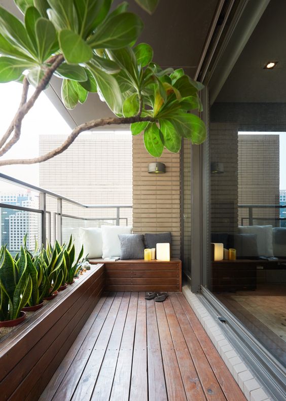 a minimalist terrace with a wooden deck and a built-in bench, a built-in planter with lots of succulents and some pillows is a lovely space to relax