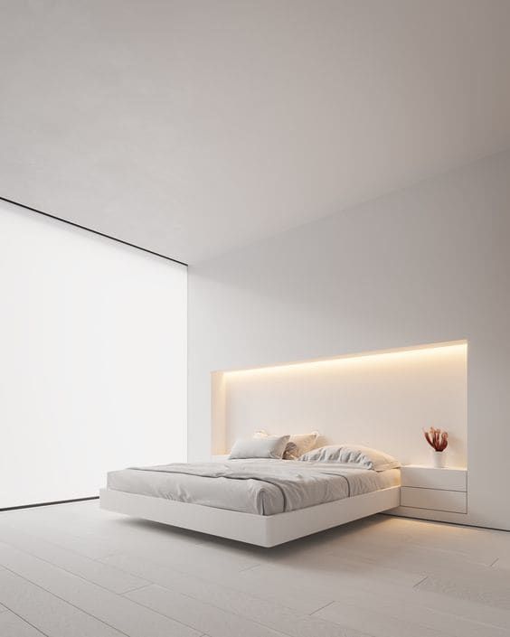 a minimalist white bedroom with a glazed wall covered with a blind, a built in bed with lights over it, built in nightstands