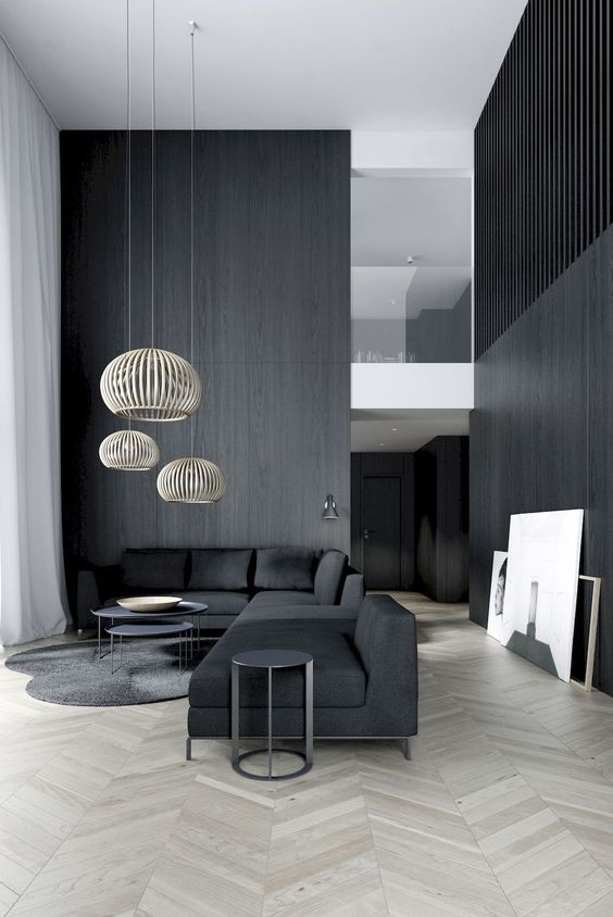 a moody minimalist living room with black walls and a sectional sofa, rattan lampshades and a couple of coffee tables