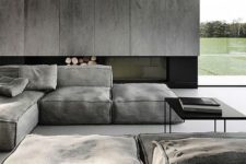a moody minimalist living space with grey panels, a built-in fireplace, grey canvas furniture and black touches
