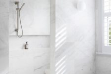 a refined white marble minimalist bathroom with a shower and bathtub space and windows is airy and serene