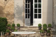 a shabby chic Provence terrace with a roudn metal table and chairs, potted greenery and lanterns is a lovely idea for a French farmhouse