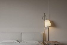 a simple and stylish minimalist bedroom with a creamy bed and bedding, a wooden stool and an elegant lamp is amazing