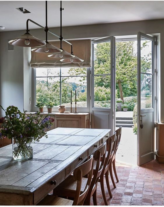 an airy Provence dining room with stained furniture with a rustic feel, a retro pendant lamp and a door to the garden