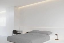 an ultimately minimalist bedroom in white, wiht a built-in floating bed, built-in nightstands and a desk, black floor lamps