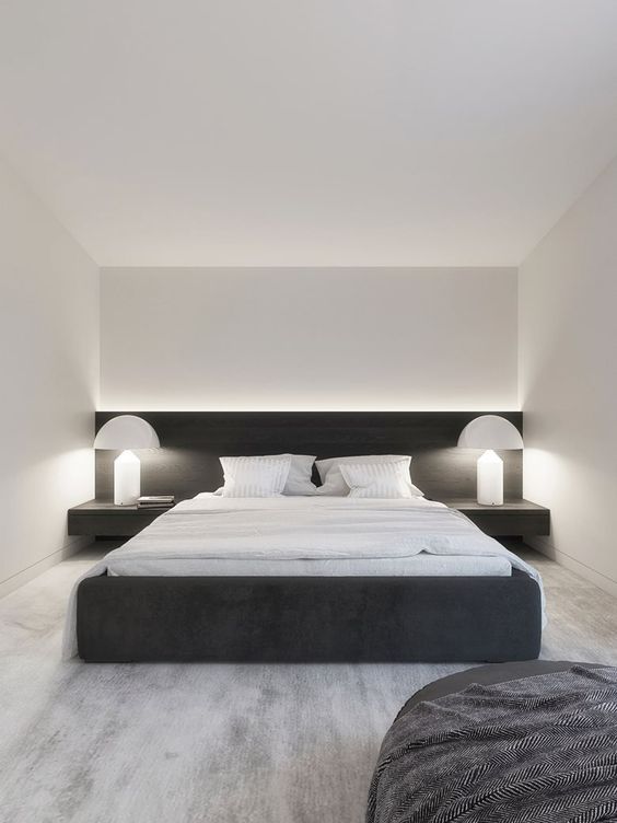 an ultra-minimal and contrasting bedroom with a black upholstered bed and black nightstands, white table lamps and white bedding