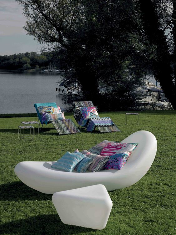 an ultra-modern white floating lounger with bright pillows and a matchign geometric side table for a modern space