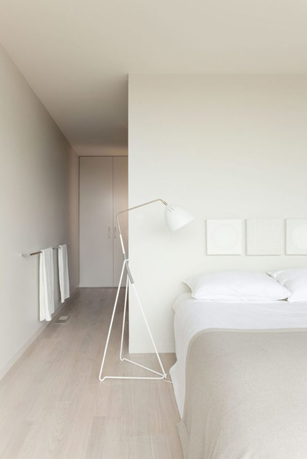 minimalist all neutral bedroom, with closed and hidden storage, a large bed, floor lamps and neutral textiles