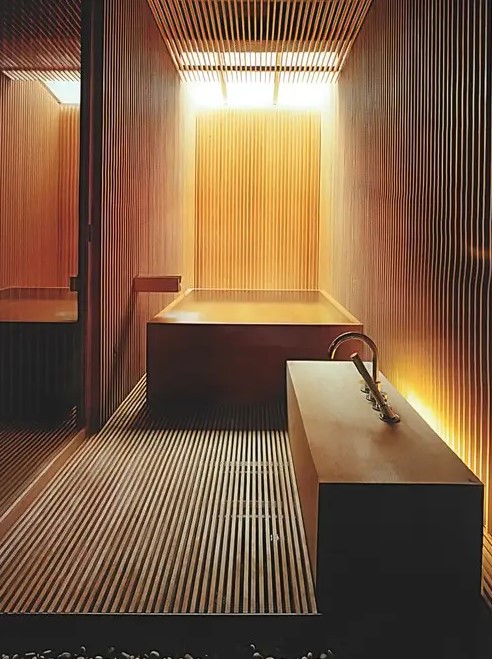 a Japanese minimalist bathroom clad with light stained wooden slabs, with a wooden bathtub nand a creative vanity with a sink plus a skylight