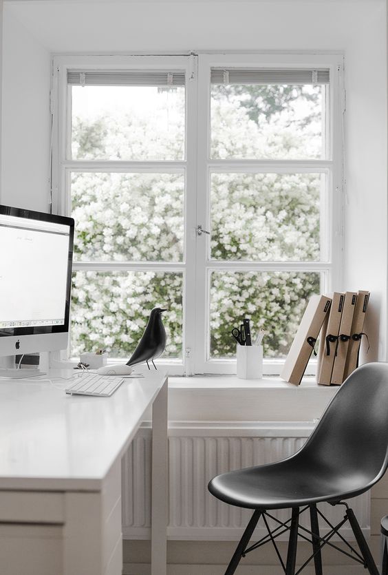 a Scandinavian home office with a window to the blooming garden, a white desk, a black chair is a pretty and cool space to work in