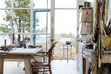 a Scandinavian studio with vintage furniture and accessories, a glazed wall and ceiling and amazing views of a water body