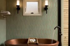 a beautiful modern spa bathroom clad with neutral and green tiles, with a glazed wall, an oval copper tub and black fixtures