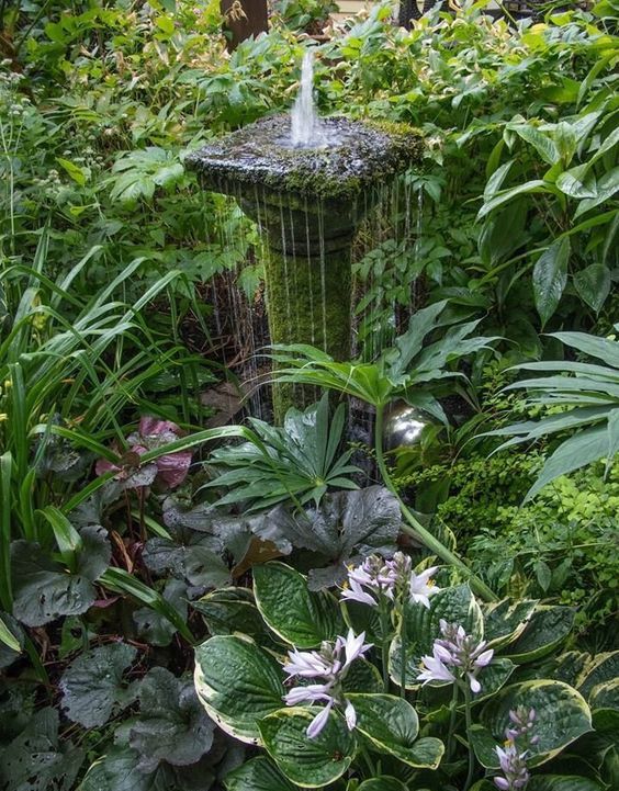 a beautiful stone and moess covered small fountain right in the center of greenery is a gorgeous idea for a vintage garden
