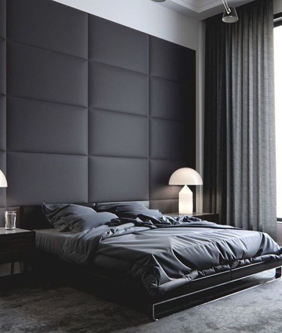 a black padded fabric statement wall perfectly fits a moody contemporayr bedroom with a masculine feel