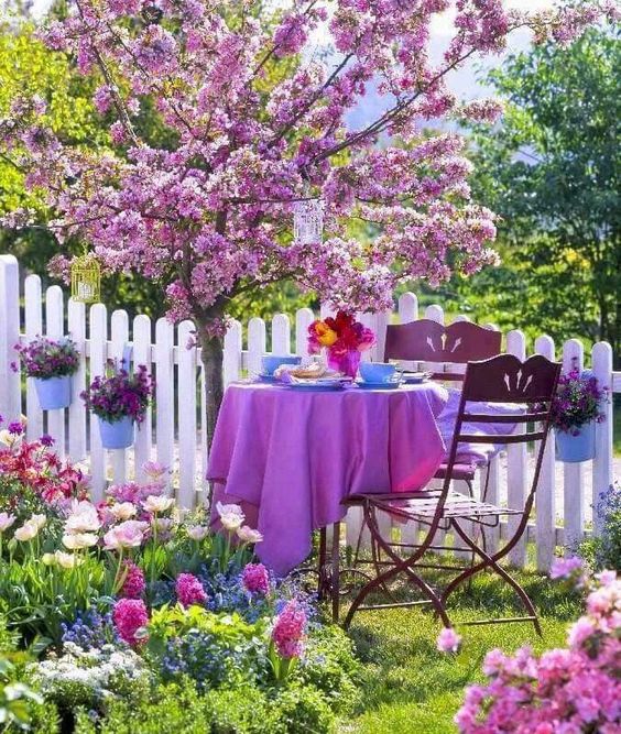 a bold pink space with blooming trees and flowers, forged furniture with purple textiles and blue tableware just wows