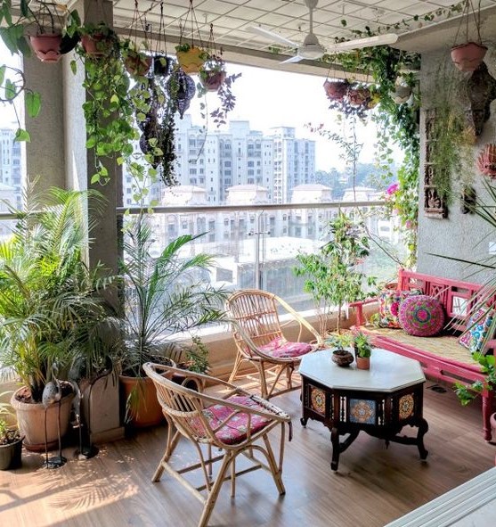 a bright boho terrace with rattan furniture and colorful upholstery, a carved wooden table, potted greenery everywhere